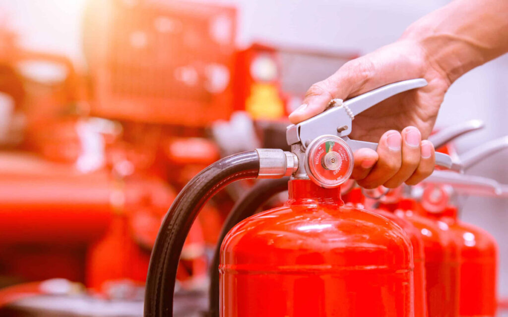 Técnico de A2J Extintores Huelva ajustando el pasador de seguridad de un extintor de incendios durante una revisión profesional